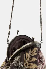 Bolso pequeño tipo sobre con cierre de clip metálico, confeccionado en tela marrón con bordados florales multicolores y aplicaciones de abalorios. Incluye una cadena metálica fina para llevar al hombro.