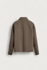 Sobrecamisa negra de corte boxy fit, confeccionada en tejido compacto. Cuenta con cuello solapa, manga larga con puños abotonados, bolsillos de parche en el pecho y cierre frontal con botones.