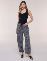 Pantalón estampado en blanco y negro con patrón de zigzag, de caída fluida, tiro alto con cintura elástica y cordón ajustable, de pernera ancha y corte cropped.