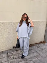 Conjunto de dos piezas compuesto por un top de cuello alto con mangas tipo capa y un pantalón de corte holgado y fluido, confeccionado en tejido de punto gris melange.