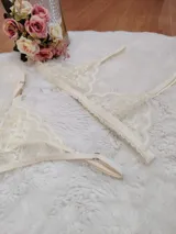 Conjunto de lencería compuesto por un corpiño triangular de encaje color champagne, con breteles regulables y terminaciones delicadas.