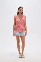 Blusa de poliéster con estampado geométrico, diseño holgado, cuello a la base y detalle de plisado en el frente.