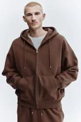 Campera con capucha H&M de corte oversized, confeccionada en tejido pesado de mezcla de algodón con interior cepillado. Presenta cierre frontal, hombros caídos, capucha forrada con cordón de ajuste y bolsillos tipo canguro. Puños y bajo acanalados.
