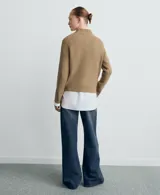 Jersey de punto color tostado con cuello alto y mangas raglán con líneas blancas decorativas en los hombros.