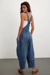 Jardinero de denim azul con silueta holgada tipo balloon, tirantes ajustables, bolsillos delanteros de parche y botones laterales.