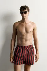 Short de baño confeccionado en tejido técnico, con diseño de rayas verticales en color verde y negro. Cuenta con cintura elástica ajustable con cordón, bolsillos laterales y bolsillo trasero con vivo, además de forro interior.