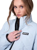 Campera matelaseada de mujer marca Caterpillar, color celeste, con cuello alto, cierre frontal central, bolsillos laterales con cremallera y parche con logo de la marca en el pecho.