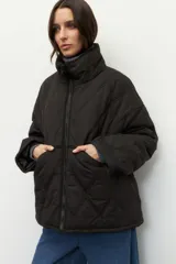 Campera corta color marrón con diseño capitoneado de rombos, cuello alto y bolsillos frontales grandes.