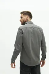 Camisa de manga larga lisa con cuello clásico y cierre frontal de botones. Presenta un ajuste regular y un pequeño logo bordado en el pecho.