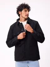 Campera de gabardina negra, con cuello camisero, cierre frontal de cremallera y botones a presión. Posee múltiples bolsillos frontales con solapa y puños ajustables con botones.