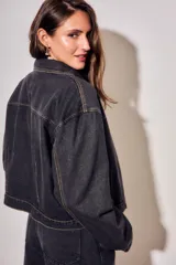 Campera oversize de denim negro, con cuello camisero, cierre frontal con botones y bolsillos ojal.