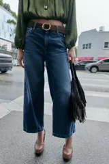 Jeans de tiro alto con pernera ancha y corte cropped. Presenta diseño de cinco bolsillos, cierre frontal con cremallera y botón, e incluye un cinturón a juego.