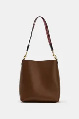 Bolso de hombro tipo saca en color marrón, con diseño minimalista y cierre de clip metálico. Incluye una correa de hombro con detalles troquelados en contraste y herrajes dorados.
