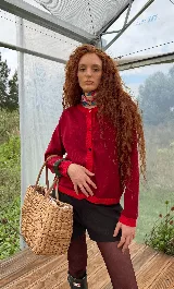 Saco de punto negro con detalles en contraste color rojo en el cuello y ruedo, y color turquesa en la botonera y puños. Presenta cierre frontal con botones y diseño de manga larga.