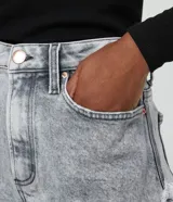 Short hot pants de jeans color gris claro con cintura alta, cierre con cremallera y botón, bolsillos y terminación deshilachada.
