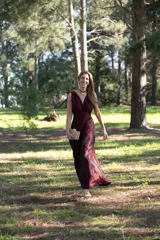 Vestido largo de tafeta color bordó, de corte estilo reloj de arena, sin mangas y con escote en V pronunciado.