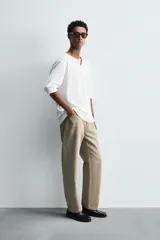 Camiseta de manga larga blanca, corte relajado, con cuello redondo y tapeta de botones (cuello panadero o henley).