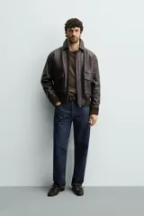 Cazadora relaxed fit de piel color marrón oscuro, con cuello solapa, manga larga y dos bolsillos plastrón con solapa en la cadera. Presenta detalle de bolsillo interior, efecto lavado y acabados en rib. El cierre frontal es con cremallera oculta por solapa con botones a presión.