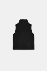 Chaleco fluido color marrón con cuello subido, sin mangas. Presenta cierre frontal de cremallera metálica y detalles de lazadas ajustables en el cuello y la cintura.