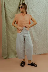 Pantalón de corte ancho y silueta abombada, color gris claro, con bolsillos frontales y costuras decorativas verticales.