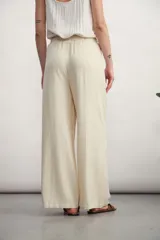 Pantalón de corte ancho y tiro alto, confeccionado en tejido de textura natural. Presenta cintura elástica con cordón ajustable, bolsillos laterales tipo parche y diseño de pierna recta y holgada.