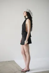 Minivestido negro de algodón con cuello halter y espalda descubierta. Se ata detrás del cuello y tiene una faja en la cintura.