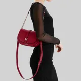 Cartera Guess tipo bandolera y bolso de hombro, color rojo con herrajes dorados y el logo de la marca en el frente. Cuenta con solapa frontal con cierre magnético, detalles de tiras con hebilla y una correa combinada de cuero sintético y cadena metálica.