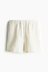 Short de corte relajado confeccionado en una mezcla de lino y algodón, con cintura elástica ajustable mediante cordón, bolsillos laterales y bolsillos traseros insertados.