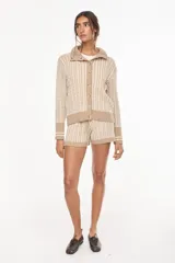 Cardigan de punto con patrón trenzado, color crudo y visón, con cuello solapa, cierre frontal de botones y mangas largas con puños elásticos rayados.