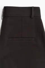 Pantalón amplio color negro, de corte holgado con pinzas, cierre con botón y corchetes ocultos, bolsillos laterales y piernas con pliegues adelante y atrás.