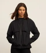 Campera deportiva cortaviento color blanco, con capucha ajustable, cierre frontal por cremallera y diseño de corte holgado. Incluye saquito para guardar.