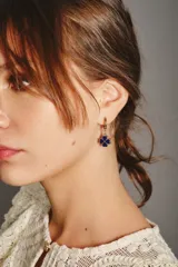 Aro tipo argolla dorada con dije colgante en forma de trébol de cuatro hojas esmaltado en azul.