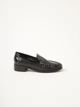 Mocasines de cuero negro con costuras pespunteadas en hilo blanco a contraste, diseño fruncido en la puntera, talón plano con pequeño tacón y apliques sutiles en charol.
