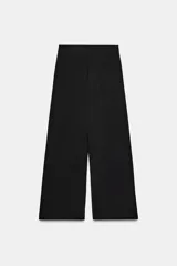 Pantalón de tiro medio color marrón, con pinzas en el delantero, perneras anchas de corte recto y trabillas para cinturón. Cuenta con bolsillos laterales y traseros, y cierre frontal con cremallera y botón.