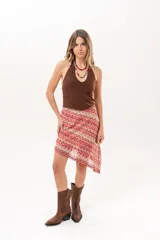 Pollera midi de corte asimétrico con tejido de crochet y patrón en zigzag multicolor en tonos rojo, rosado y beige.