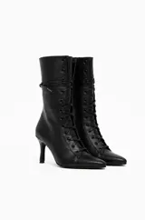 Botas de caña media con diseño acordonado frontal tipo corset, punta fina y taco fino. Cuentan con cierre lateral para facilitar el calce.