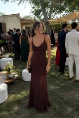 Vestido corto de microtul color marrón con diseño de doble capa, que incluye una base opaca y una capa exterior semitransparente. Presenta escote drapeado, tirantes finos y un ajuste ceñido al cuerpo con efecto fruncido lateral.