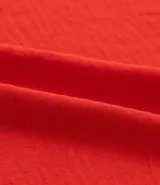 Blusa roja de crepé con escote en pico y volados dobles en los hombros. Sin mangas y de calce holgado.