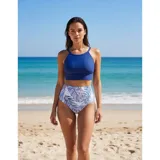 Bikini de dos piezas con top liso de cuello redondo y bombacha de tiro alto con estampado botánico de hojas en tonos azules y blancos.