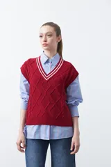 Chaleco de punto color bordó, con diseño de rombos y trenzas en relieve. Escote en V con ribete blanco y rojo.