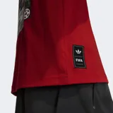 Remera Adidas de corte holgado en color rojo, confeccionada en algodón. Presenta un parche gráfico en el pecho con el logo de la marca y un balón de fútbol, además de un detalle de etiqueta en el ruedo inferior.