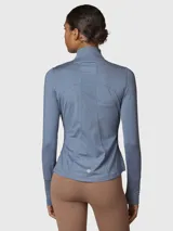 Campera deportiva de ajuste entallado, confeccionada en tejido técnico suave de color azul melange. Presenta cuello alto con cierre frontal, mangas largas con orificio para pulgar y bolsillos laterales con cierre.