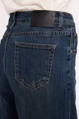 Jean de tiro alto en color azul oscuro, con costuras verticales decorativas en el frente y cierre de botón metálico.