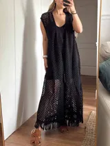 Chaleco largo sin mangas, tejido en punto calado tipo red con hilo de algodón y lurex, color marrón. Presenta escote profundo en V, tiras para atar en el frente, tajo trasero y flecos en el ruedo.