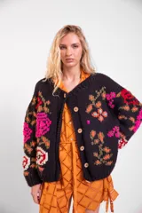 Cardigan de lana merino tejido y bordado a mano de calce holgado con cuello a la base, mangas largas y cierre frontal de botones. Presenta un diseño artesanal con bordados coloridos en las mangas y el cuerpo.