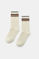 Calcetines de color beige con diseño de rib y dos rayas horizontales de hilo metalizado marrón y una raya negra en el borde superior.