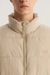 Campera puffer color beige con cierre frontal y cuello alto.