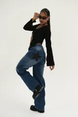 Top negro de tejido texturizado, manga larga acampanada y escote pronunciado que se ata con un nudo central, dejando el abdomen al descubierto.