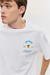 Remera blanca de algodón con cuello redondo, manga corta y pequeño estampado en el pecho.