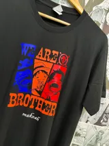 Remera negra de algodón con estampado de personajes de One Piece en colores azul, naranja y rojo.